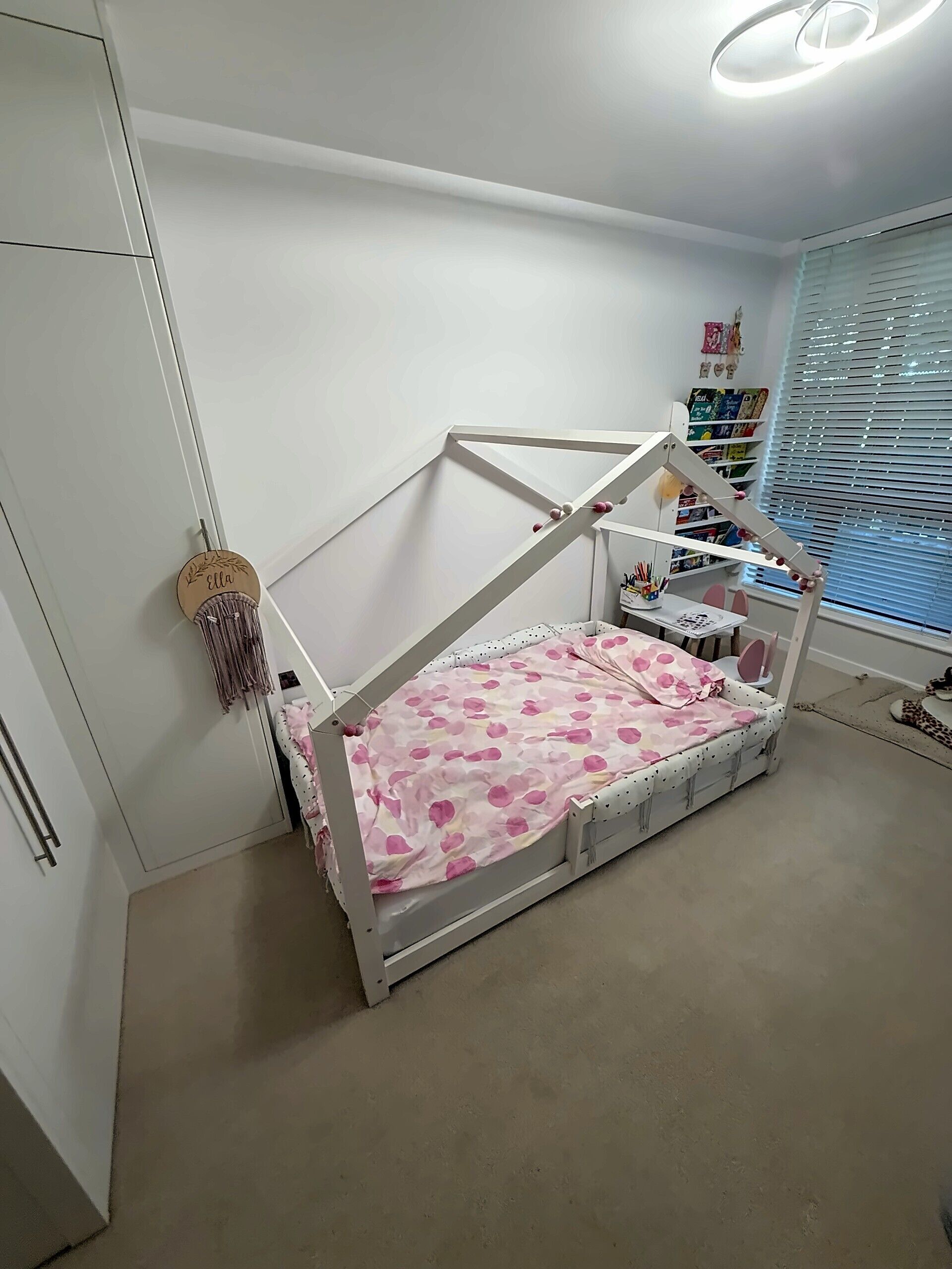 A bedroom with a bed, a wardrobe, a desk, and a window with blinds.