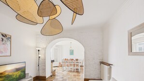 Een woonkamer met een televisie, een bank en een eethoek met stoelen.