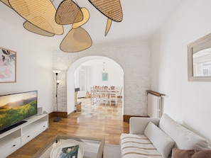 Ein Wohnzimmer mit Fernseher, Sofa und Essbereich mit Stühlen.