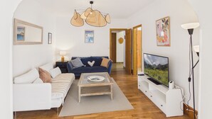 Een woonkamer met een bank, een salontafel, een televisie en een kroonluchter.
