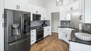 Una cocina moderna con armarios blancos, electrodomésticos de acero inoxidable y una encimera negra.