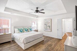 A bedroom with a bed, a ceiling fan, a nightstand, a lamp, a painting, and a door. - Step-Free Family Home with BBQ in Montgomery (Montgomery)