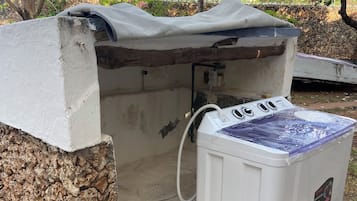 Aquecedor de água em ambiente externo, com parede de pedra e área coberta.