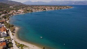 Un pueblo costero con una playa, aguas azules cristalinas y montañas al fondo.