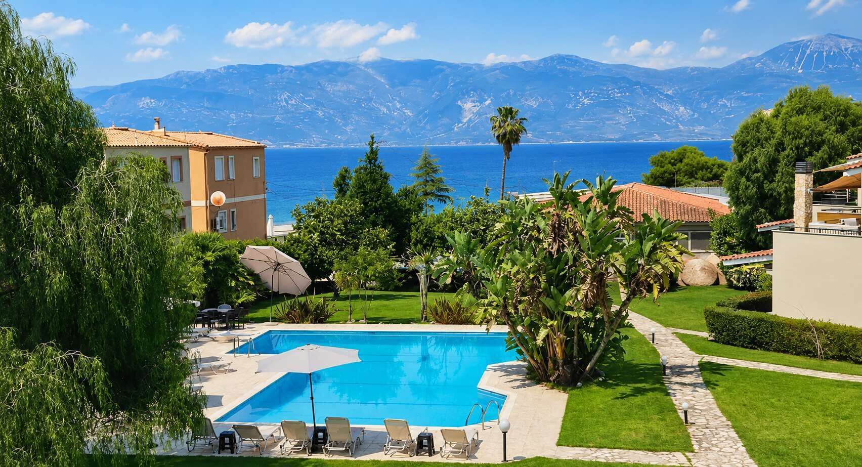 Shared swimming pool surrounded by landscaped gardens, offering plenty of space for sunbathing, relaxing, and enjoying the peaceful atmosphere just steps from the beach.