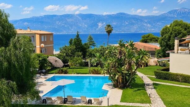 Una piscina con sillas de descanso, un patio y vistas al mar y a las montañas.