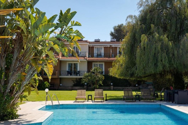 View of the complex from the pool area, combining Mediterranean gardens, comfortable accommodations, and easy access to the beach and village amenities.