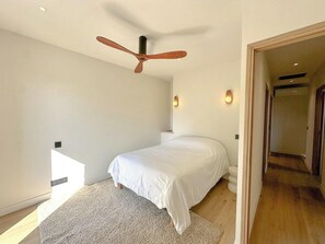 Ein Schlafzimmer mit einem Bett, einem Deckenventilator, einer Lampe und einem Teppich.