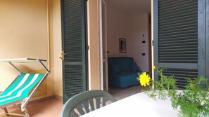 A balcony with a chair, a table, and a potted plant. - Elba, Nisportino. Two-room apartment with a patio overlooking the sea. The Sea, Sunsets, and Tranquility (Toscana)