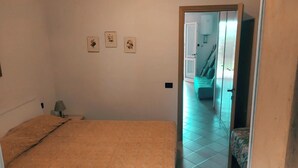 Een slaapkamer met een bed, een nachtkastje en een lamp. Drie ingelijste foto's hangen aan de muur.