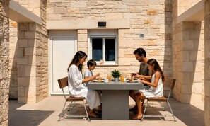 A family dining outdoors at a stone building with a table, chairs, and a window. - Marea Maxima Villa 2 Heated Pools (Dramia)
