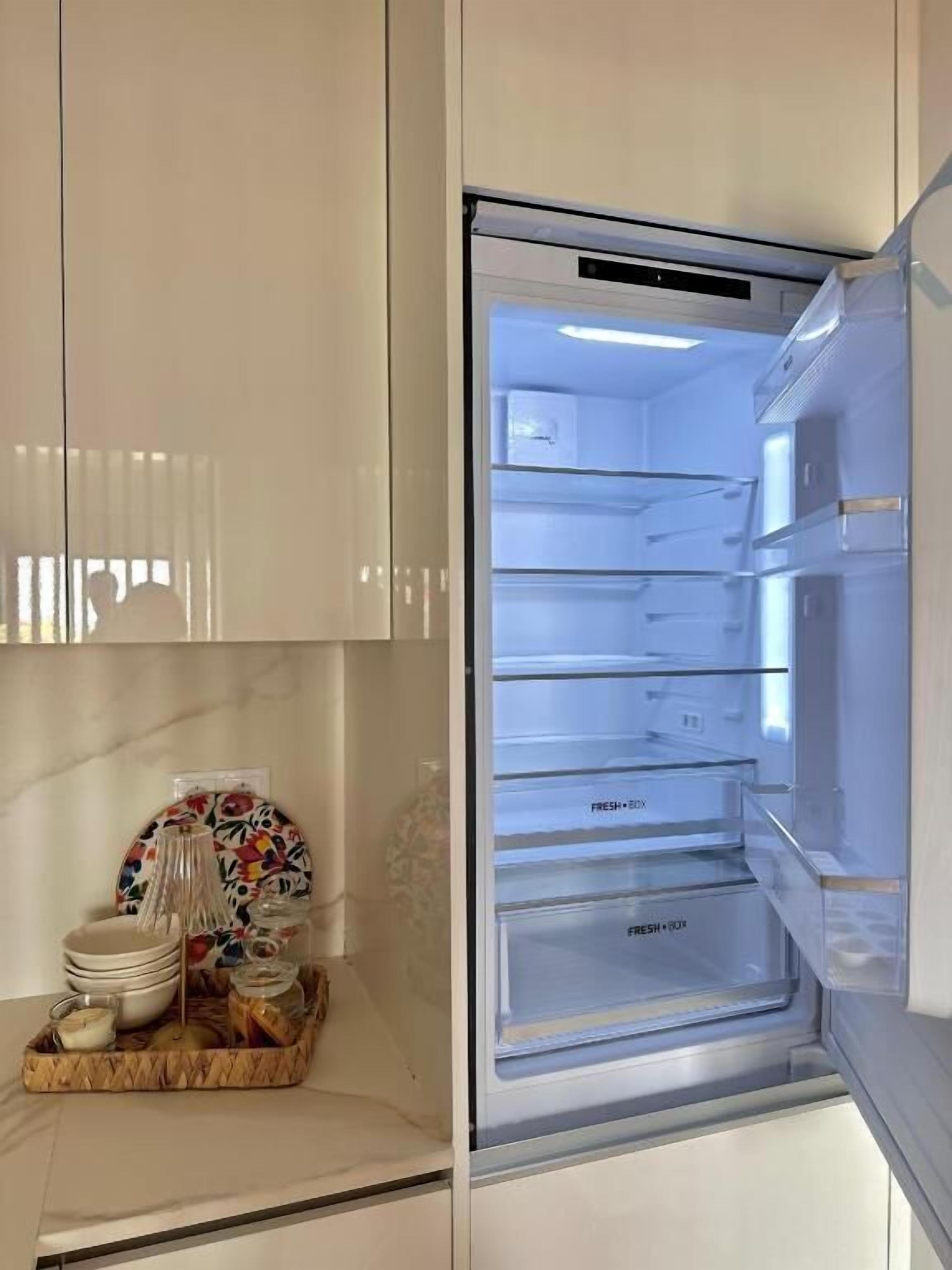 Ein offener Kühlschrank mit mehreren Ablagen und einem Gefrierfach.