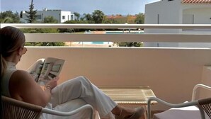 Ein Balkon mit einer Person, die ein Buch liest, einem Stuhl und einem Tisch.