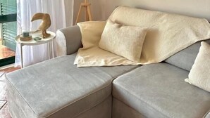 Ein modernes Wohnzimmer mit einem grauen Ecksofa, einer stehenden Stehlampe und einer Wand-Klimaanlage.