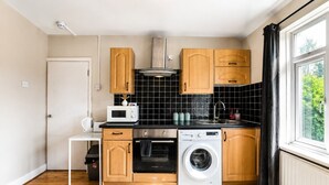 Een compacte keuken met houten kastjes, een magnetron, een oven en een wasmachine.