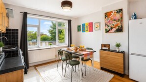 Een moderne keuken met een eethoek, grote ramen en uitzicht op groen.