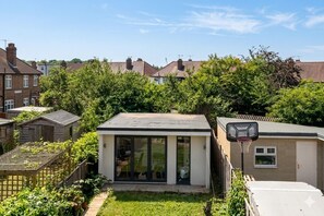 A modern house with a glass door entrance, a basketball hoop, and a garden area. - Spacious 3BR Flat Sleeps 7 in Greenford (London)