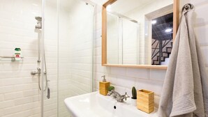 A bathroom with a glass shower enclosure, a white sink with a wooden soap dish, a mirror, and a towel hanging on the wall. - Modern stylish apartment @ Superb central location (R) (Budapest)