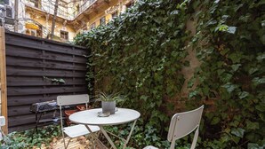 A patio with a round table and two chairs, surrounded by a wooden fence and a wall covered in ivy. - Modern stylish apartment @ Superb central location (R) (Budapest)