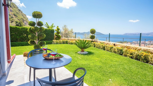 Une terrasse avec une table, des chaises et un panier de fruits, ainsi que des verres à vin.
