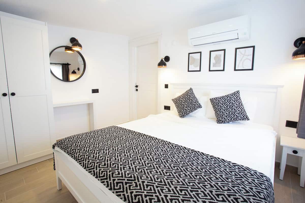 A bedroom with a bed, a wardrobe, a mirror, and wall-mounted lights.