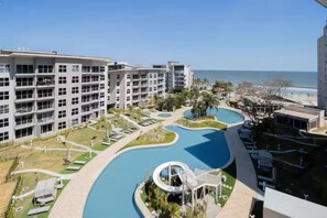 Et hotel med flere etager, en swimmingpool og udsigt over havet.