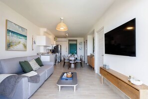 Eine moderne Wohnung mit Wohnzimmer, Küche, Essbereich und einem an der Wand befestigten Fernseher.
