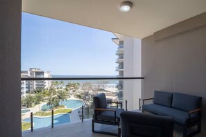 Un balcon donnant sur une piscine et des immeubles, avec un canapé et un fauteuil.