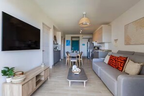 A modern living room with a flat-screen TV, a sofa, a coffee table, and a dining area with chairs and a table. - Lindo apartamento con vista al mar y piscina (punta chame)