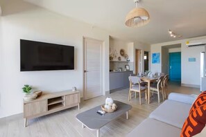Ein modernes Wohnzimmer mit Flachbildfernseher, einer Couch, einem Couchtisch und einem Essbereich mit Stühlen und einem Tisch.