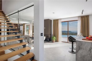 Ein modernes Interieur mit Treppe, Kamin, Essbereich und Blick ins Freie.