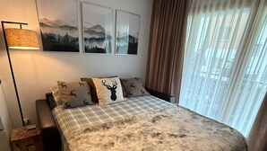 Un dormitorio con cama, mesita de noche, lámpara, ventana con cortinas y decoración en la pared.