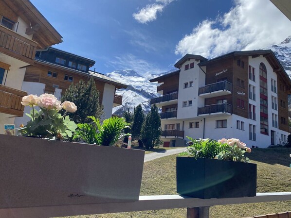 Ein Hotel mit Blick auf die Berge, Holzbalkonen und Kübelpflanzen.