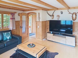 Sala de estar con sofá, mesa de centro, televisor, armarios de madera y adornos de asta.