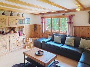 A cozy cabin interior with a wooden dining table, a sofa, and a window with curtains. - Cosy apartment for 2 people with WIFI, TV, patio, pets allowed and panoramic view (Peist)