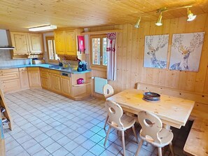 Interior de una cabaña de madera con cocina, comedor y obras de arte en las paredes.