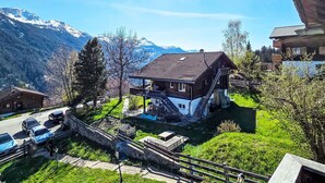Una casa con techo inclinado, balcón y vistas a montañas nevadas.