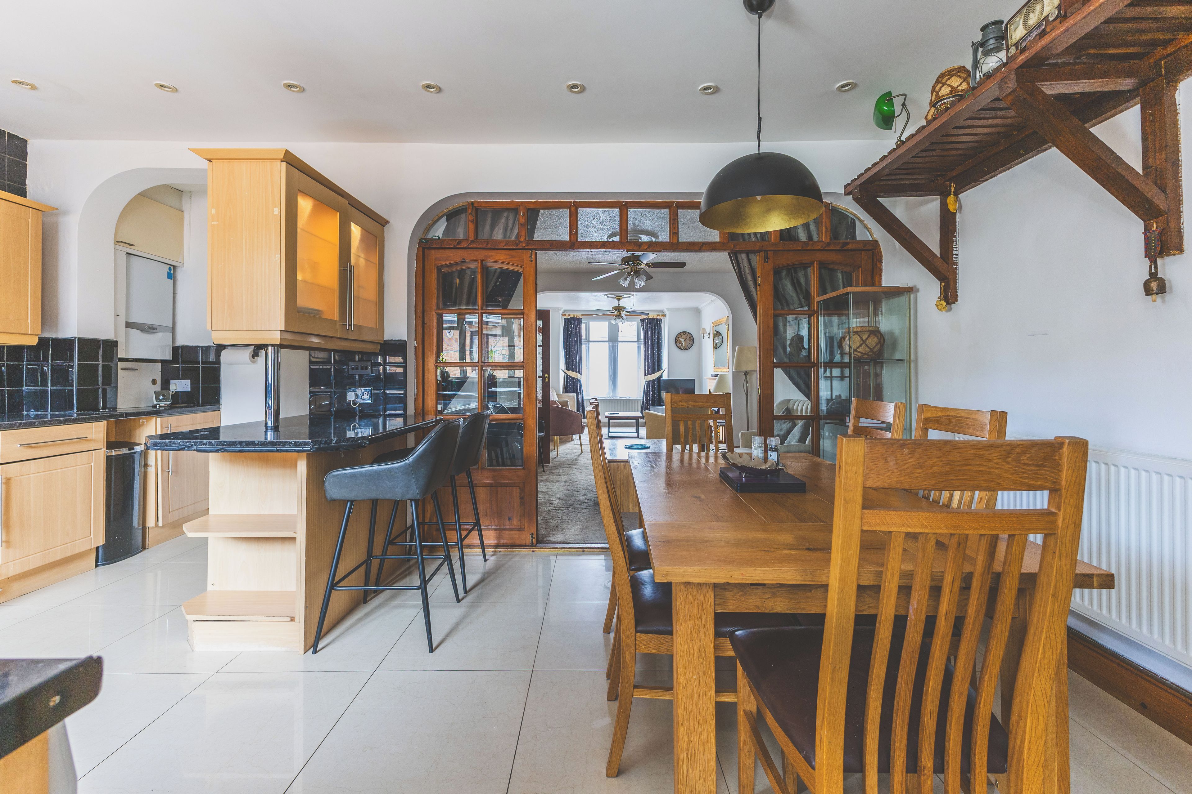 A spacious kitchen with modern appliances, a dining area with wooden furniture, and a high ceiling with exposed beams.