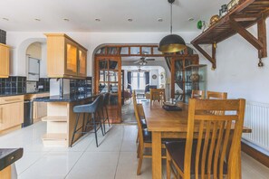 Eine moderne Küche mit Holzschränken, einer schwarzen Arbeitsplatte und einem Essbereich mit Holztischen und einem Tisch.