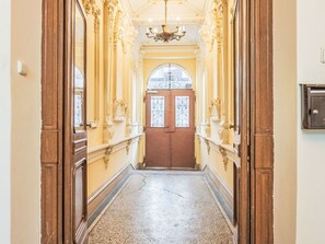 Ein Flur mit aufwendiger Stuckverzierung, einem Chandelier und Doppeltüren.
