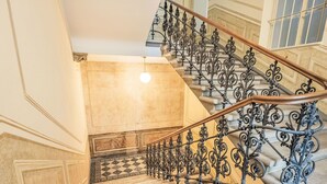 Una imponente escalera con barandillas de metal ornamentadas y un suelo con motivos.