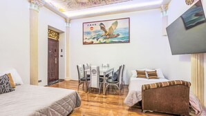 Habitación de hotel con dos camas, un escritorio, sillas, un televisor y un mural en el techo.