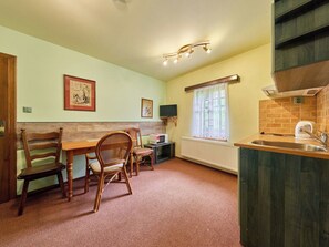A compact kitchen with a dining area, a microwave, and a window with curtains. - Nice apartment for 2 people with WIFI and TV (Jilemnice)