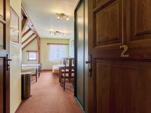 Ein Flur, der zu einem Schlafzimmer mit Bett, Fenster und Heizkörper führt. Dort ist eine Tür mit der Nummer 2.