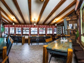 Ein Restaurant mit Holzbalken, Fliesenboden und Blick auf geparkte Autos.