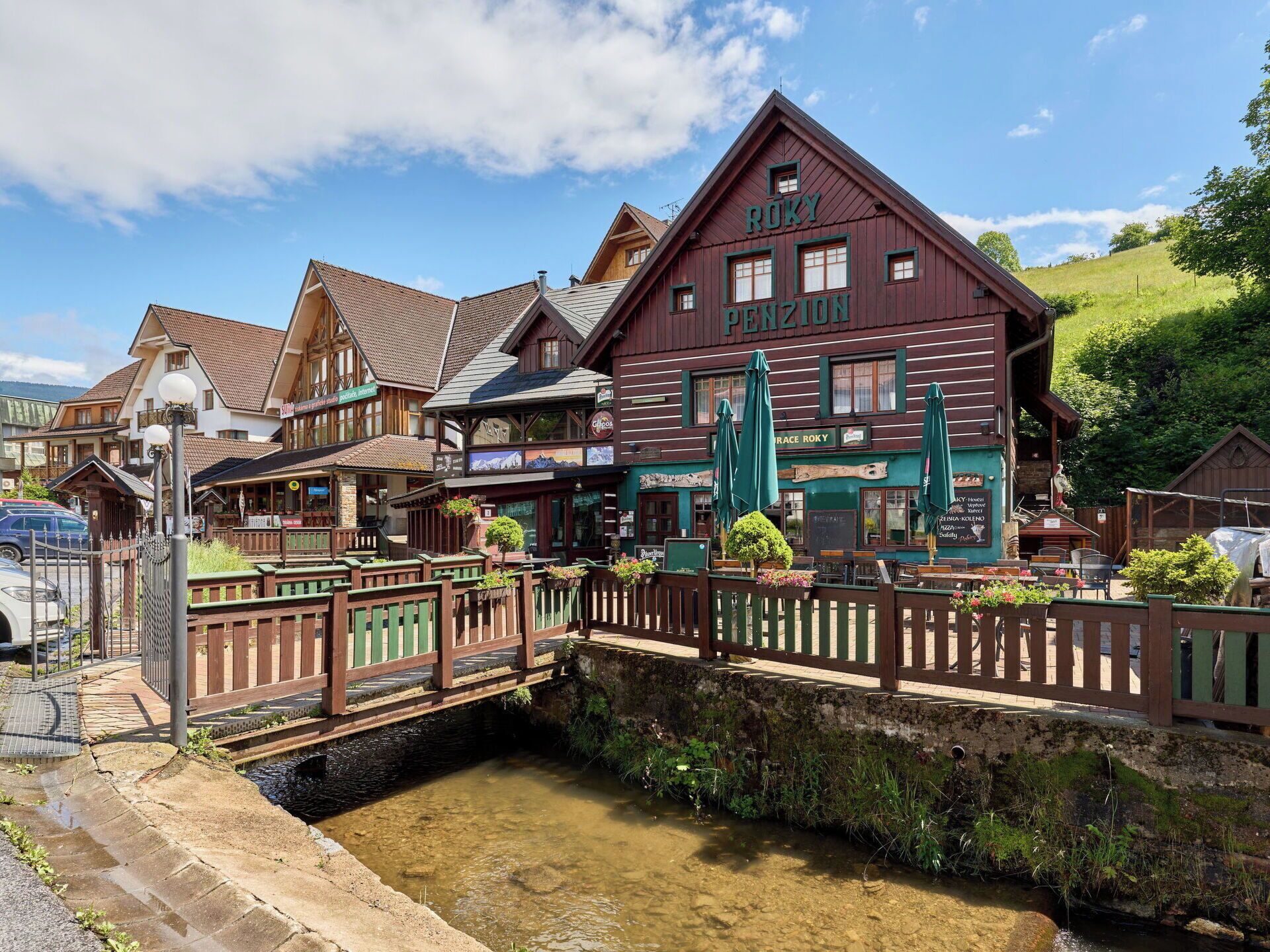 A traditional wooden building with a sign 'RUKY PENZION' and outdoor seating area.