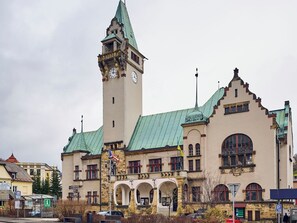 Ein historisches Gebäude mit einem Glockenturm, Bogenfenstern und einem grünen Dach.
