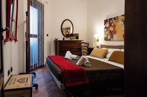 Ein Hotelzimmer mit Bett, Schminktisch, Spiegel, einem Gemälde und einem Fenster mit Vorhängen.