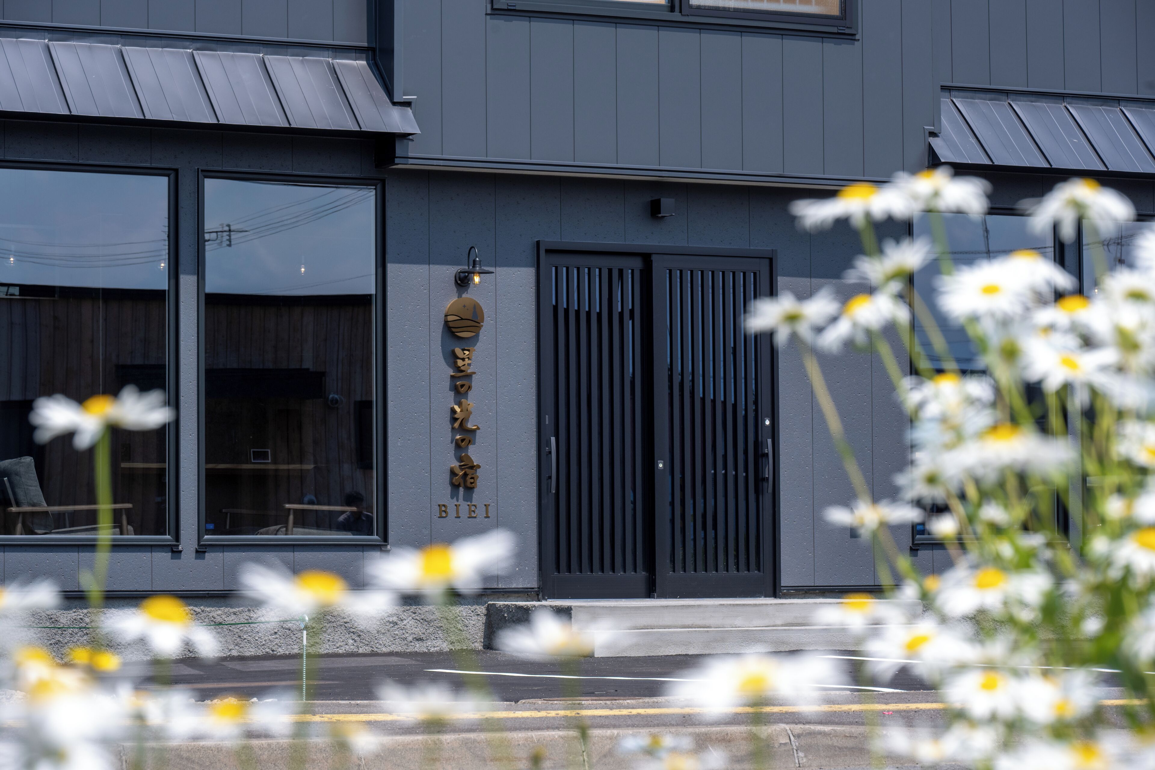 A modern building with large windows, a black gate, and a sign with Japanese characters.