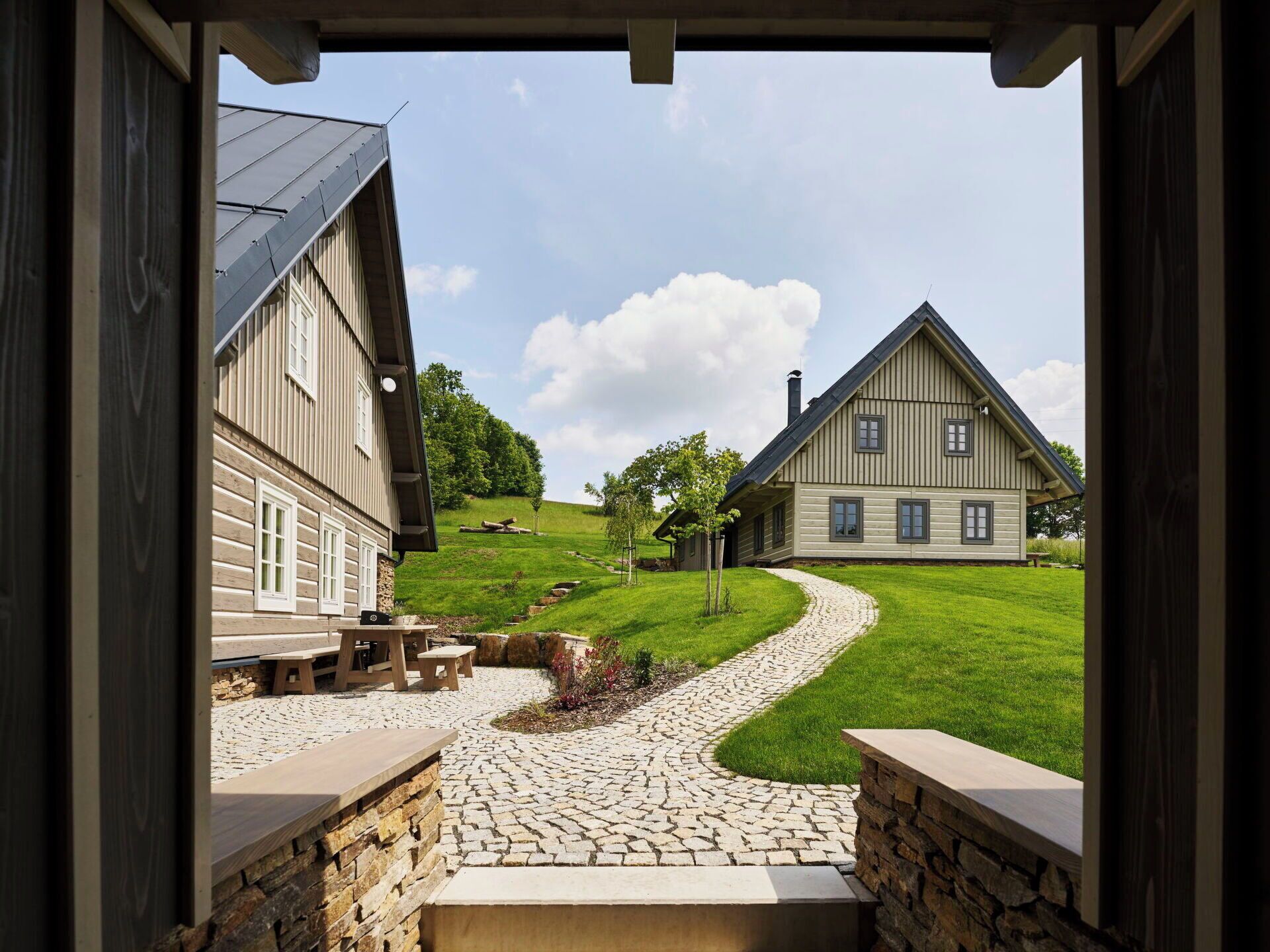 A view through an open doorway of a house with a stone pathway leading to a wooden deck.